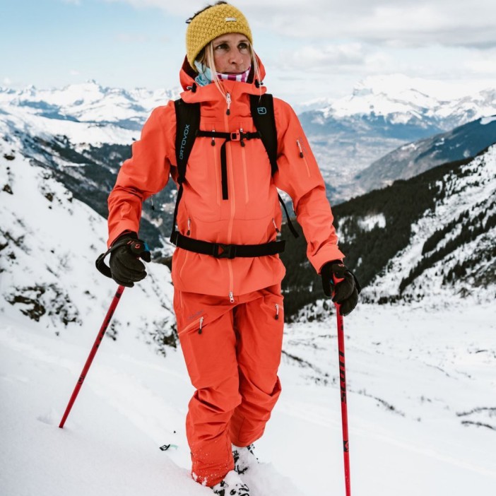 a woman wearing an orange jacket with the word ortovox on it