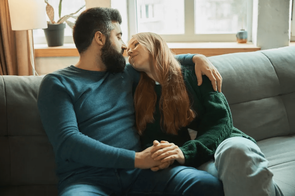 a man and a woman sitting on a couch looking at each other