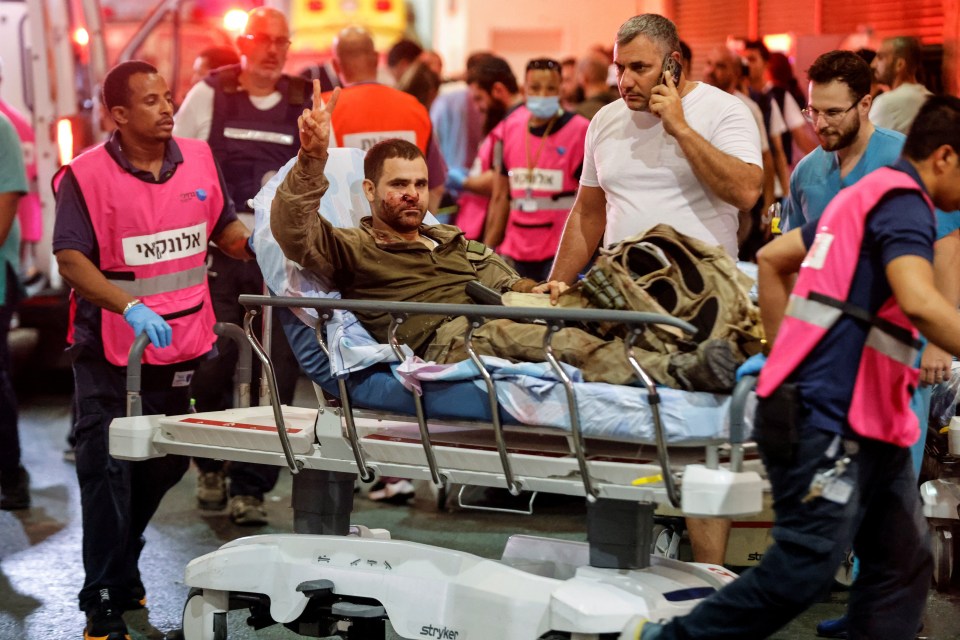 An injured Israeli officer gestures as he arrives at a hospital