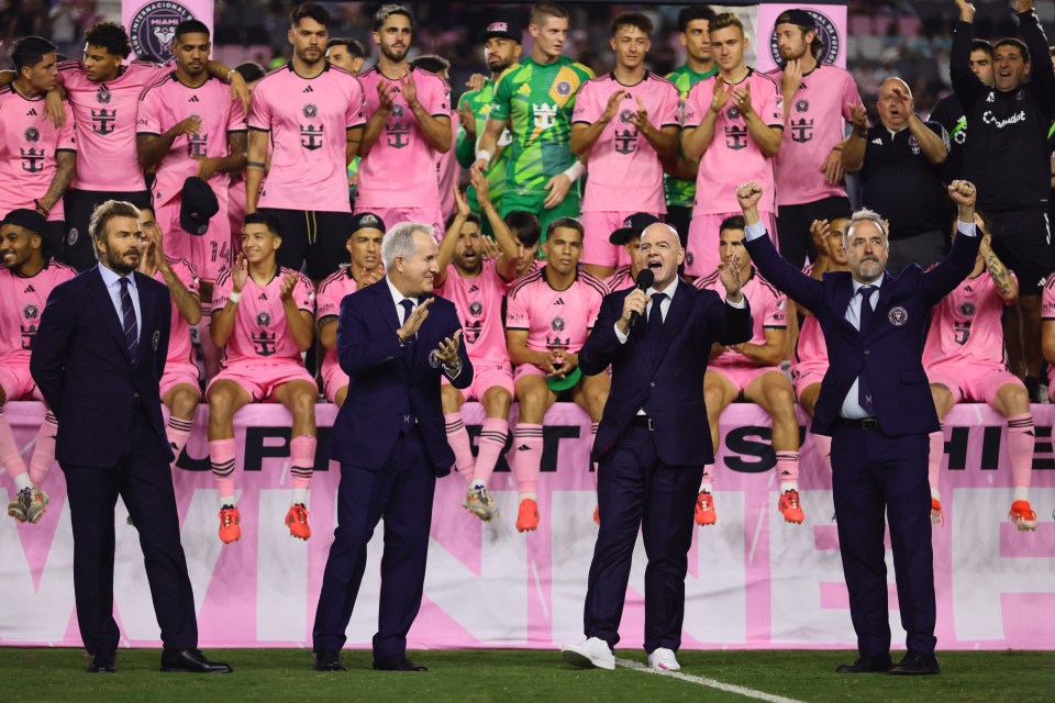 a group of men standing in front of a soccer team wearing pink jerseys