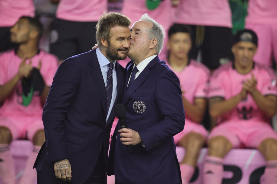 a man kisses another man on the cheek in front of a soccer team