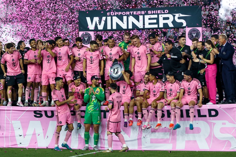 a group of soccer players are posing for a photo in front of a banner that says supporters ' shield winners