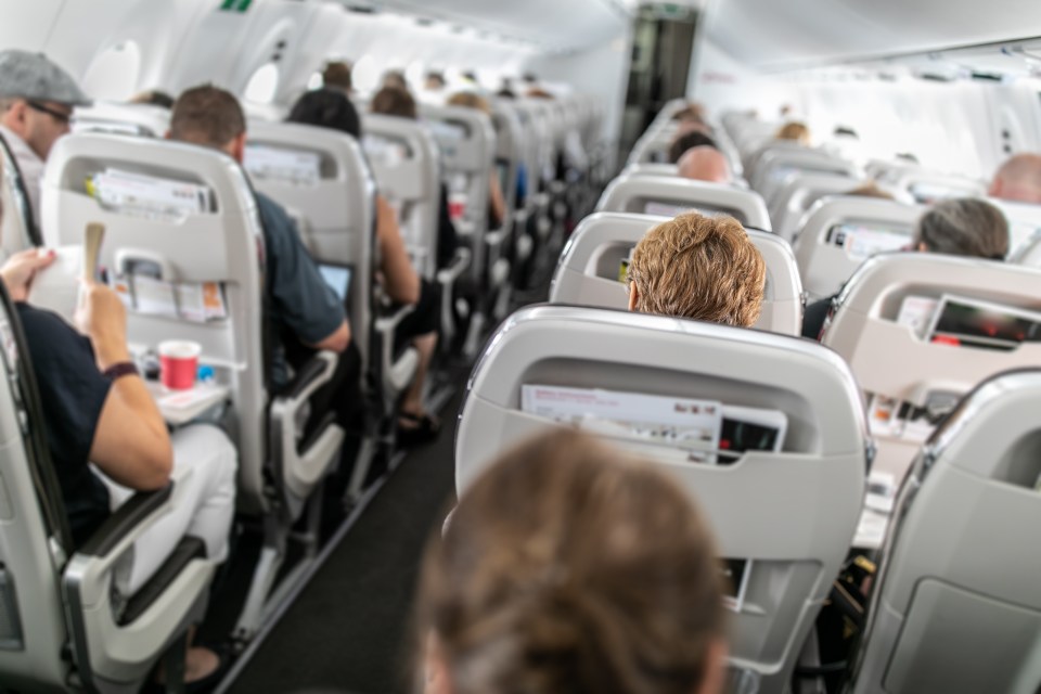 a woman sits in a row of seats on an airplane