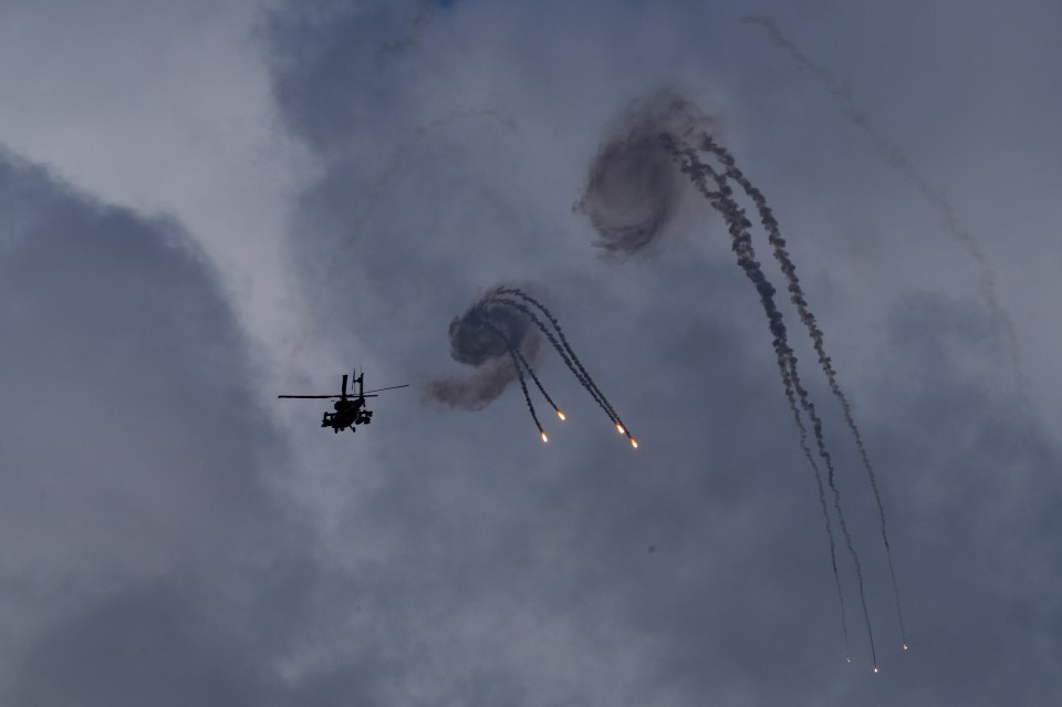 a helicopter is flying through a cloudy sky with smoke trails