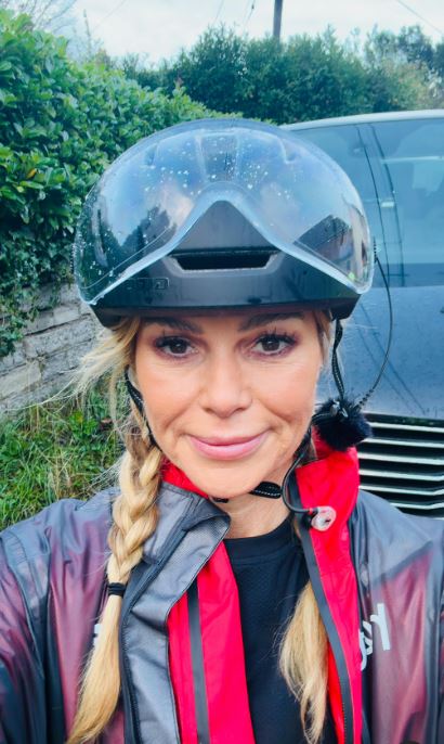 a woman wearing a helmet and goggles is standing in front of a car .