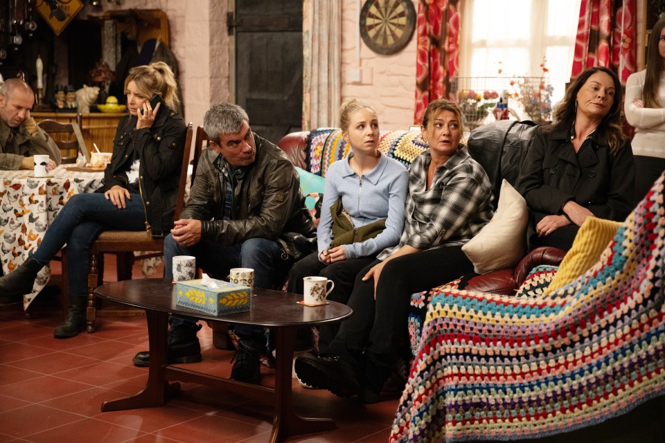 a group of people sitting around a table with a box of tissues on it