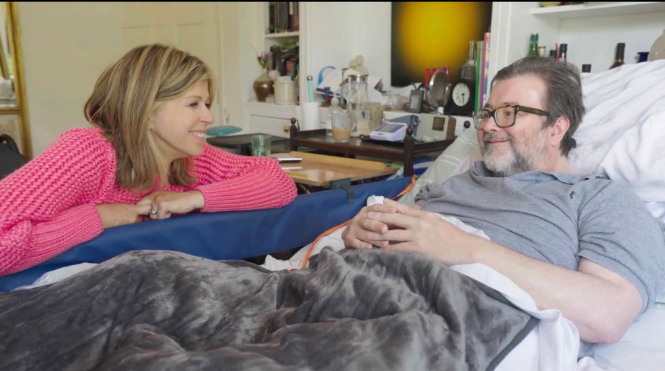 a woman in a pink sweater talks to a man in a hospital bed