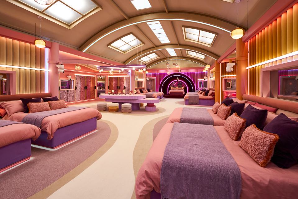 a large room with pink and purple beds and a pool table