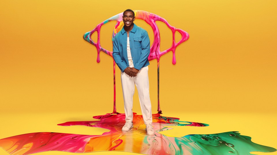 a man in a blue shirt and white pants stands in front of a colorful painting