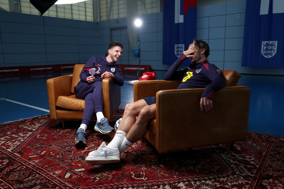 two men sit in chairs in front of a wall that says ' england 's park ' on it