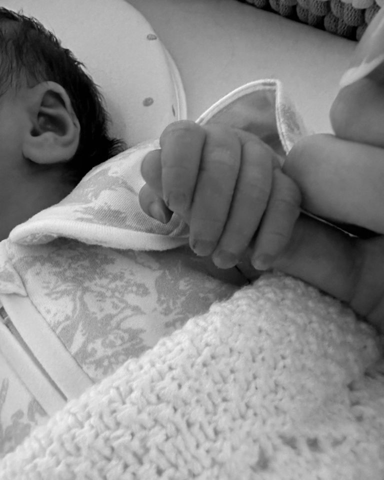 a person holding a baby 's hand in a black and white photo