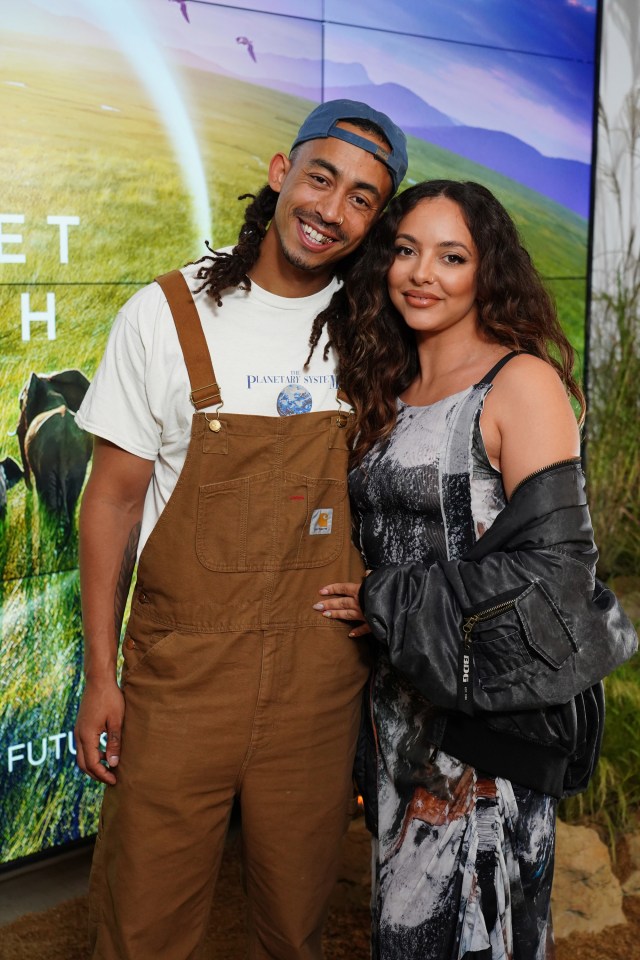 a man wearing overalls has a planet earth shirt on