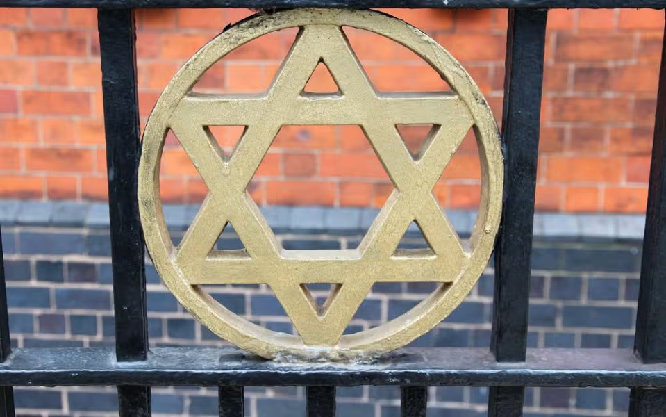 a gold star on a black fence with a brick wall in the background