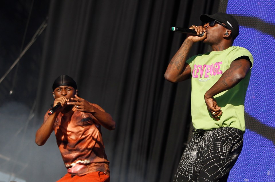 a man wearing a green shirt that says revenge is singing into a microphone