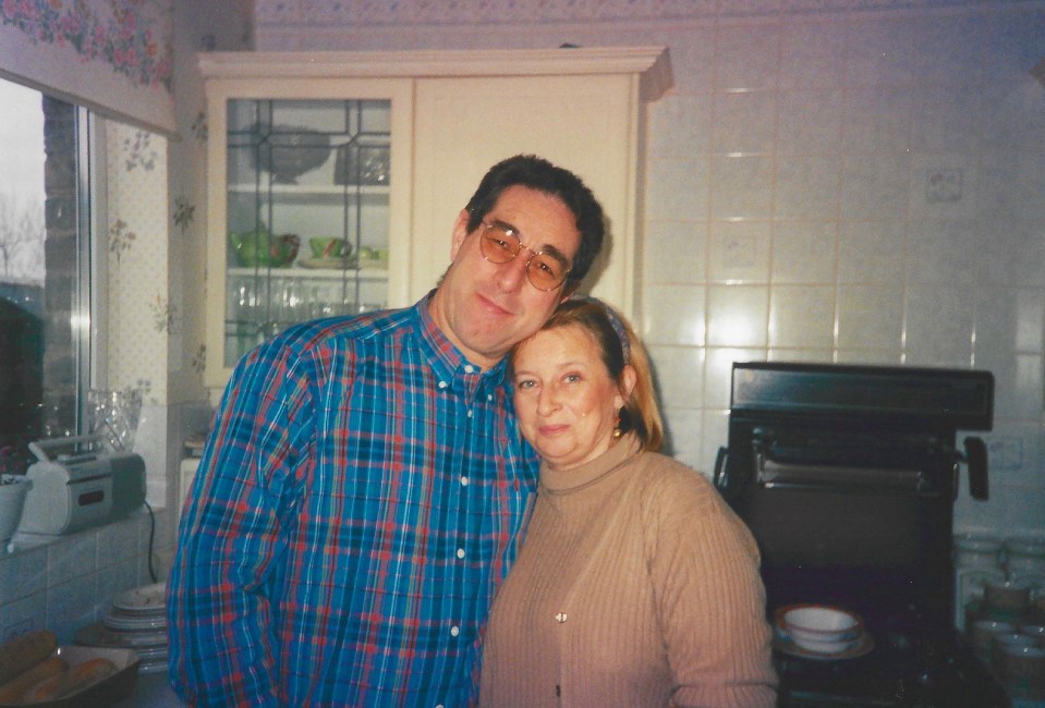 a man and a woman pose for a picture in a kitchen