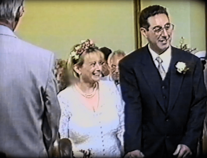 a man in a suit and tie stands next to a woman in a flower crown