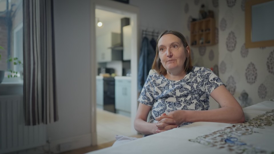 a woman in a blue and white butterfly shirt sits on a bed