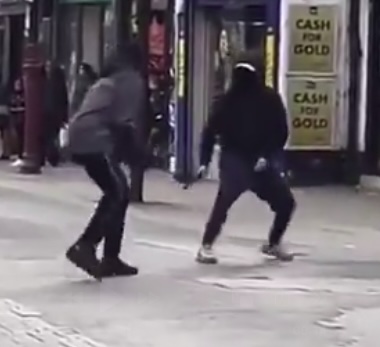 The two thugs, each armed with a machete, fight each other in the street