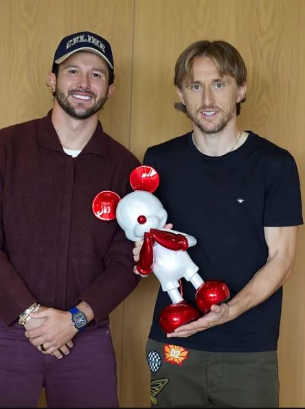 two men are standing next to each other holding a stuffed animal .