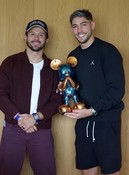 two men are standing next to each other holding a mickey mouse statue .