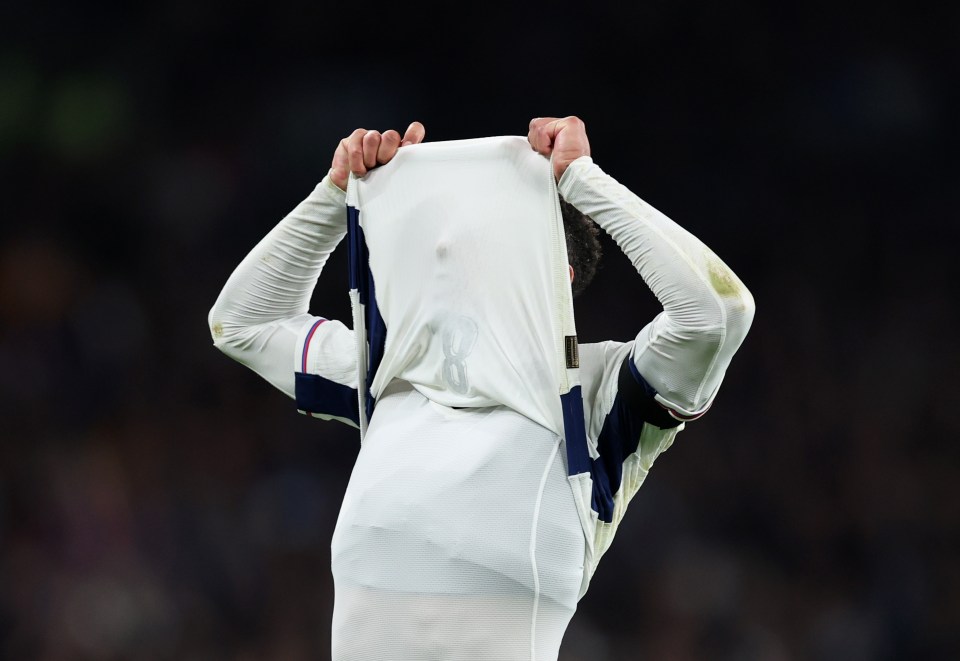 a soccer player holds his shirt up to his face