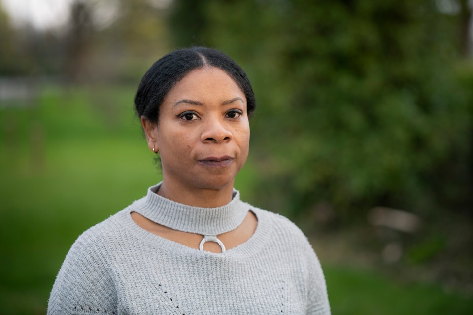 a woman wearing a grey sweater looks at the camera