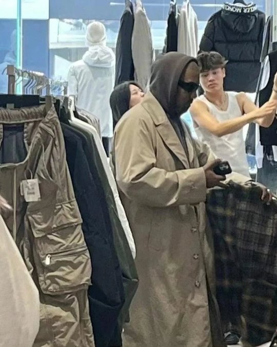 a man in a trench coat is shopping in a clothing store .