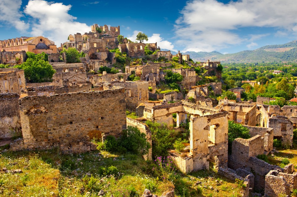 a ruined village with mountains in the background