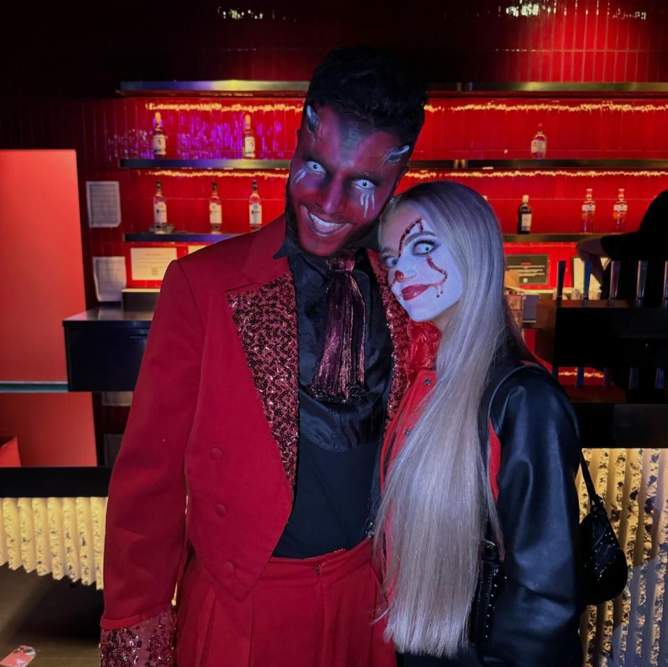 a man in a devil costume poses with a woman in a clown costume