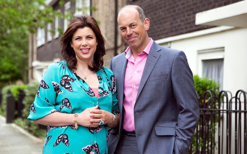 a man in a suit and a woman in a blue dress are posing for a picture