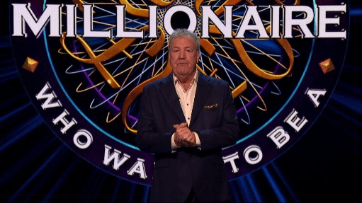 a man in a suit stands in front of a millionaire logo