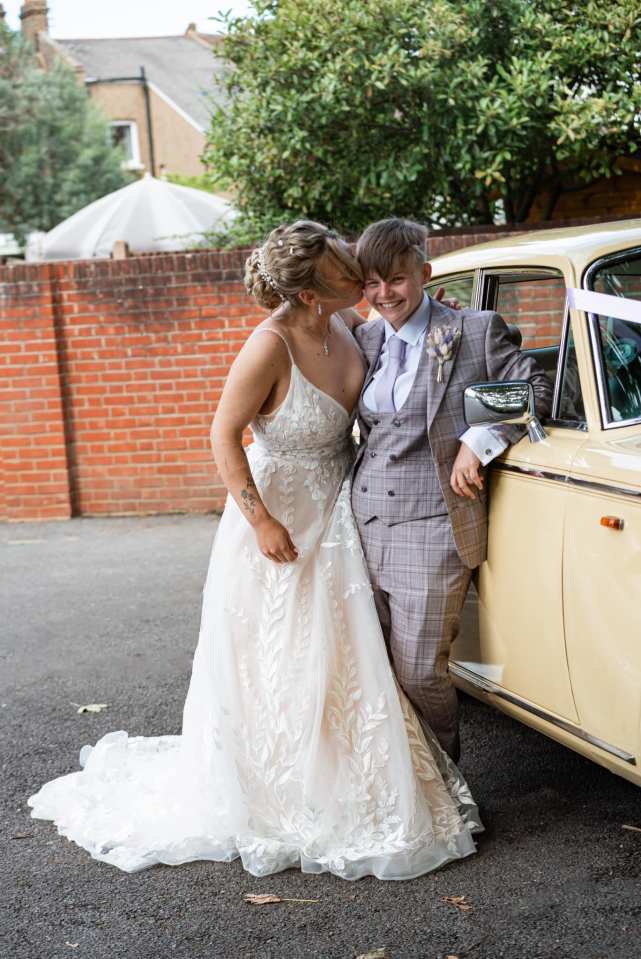 a bride and groom kissing in front of a car