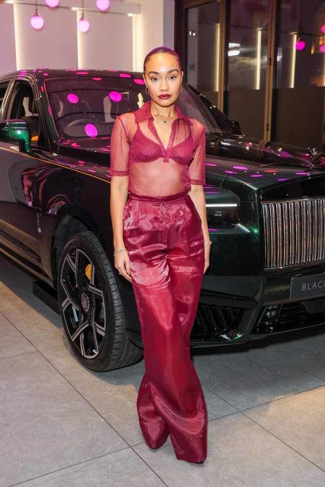 a woman stands in front of a black car