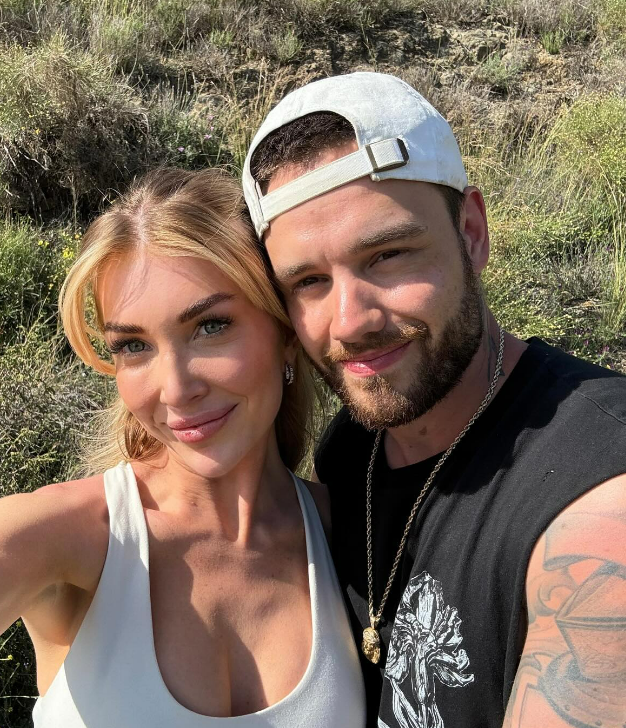 a man and a woman pose for a picture in a field