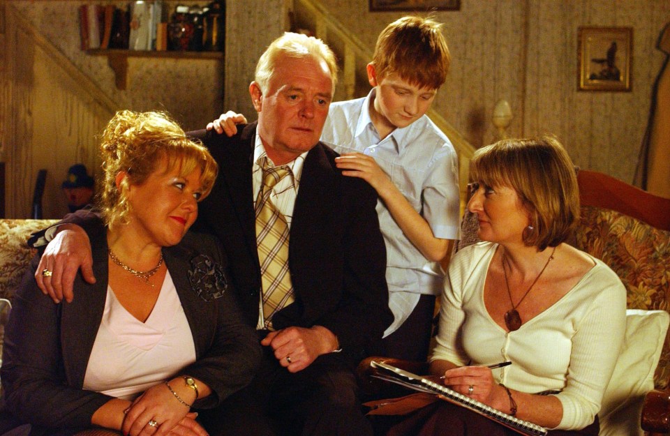 a family sits on a couch with a woman holding a clipboard