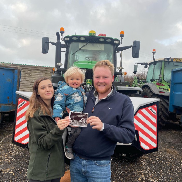 a man and woman holding a child in front of a tractor that says wih on the side