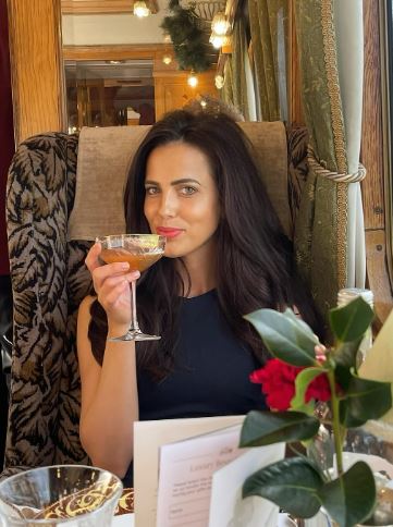 a woman is sitting in a chair holding a glass of wine .