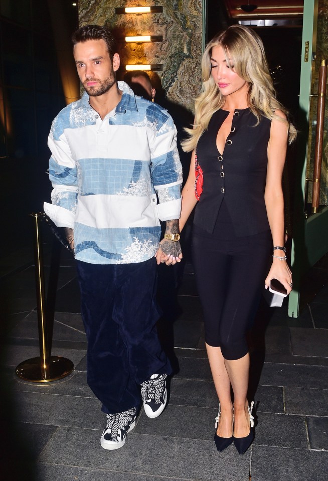 a man in a striped shirt holds hands with a woman in a black dress