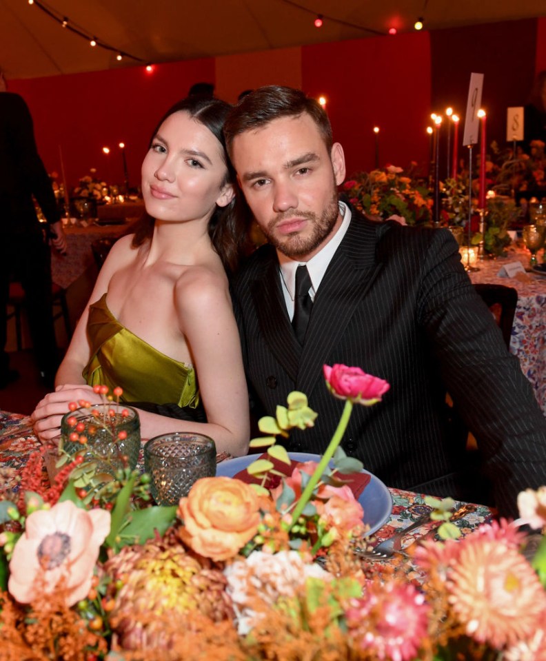 a man and a woman sit at a table with flowers