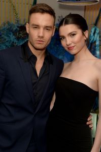 a man in a suit stands next to a woman in a black dress