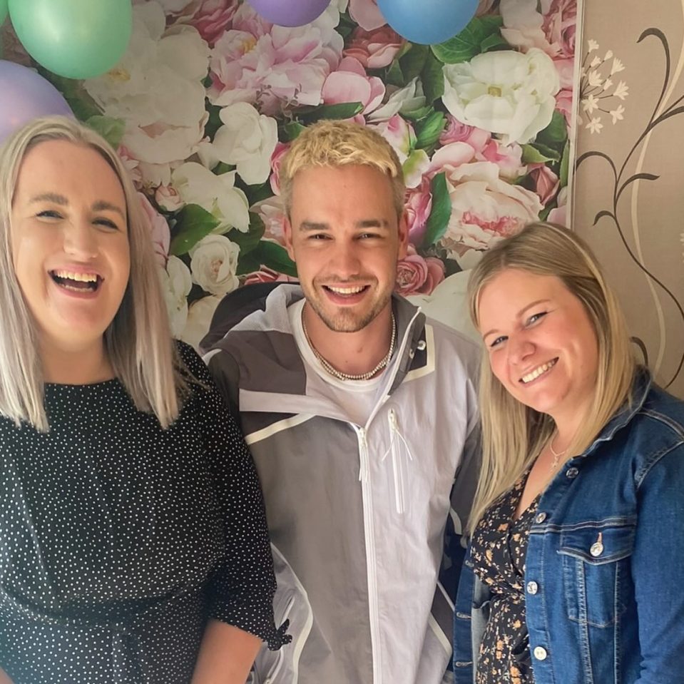 a man and two women are posing for a picture in front of a floral wall