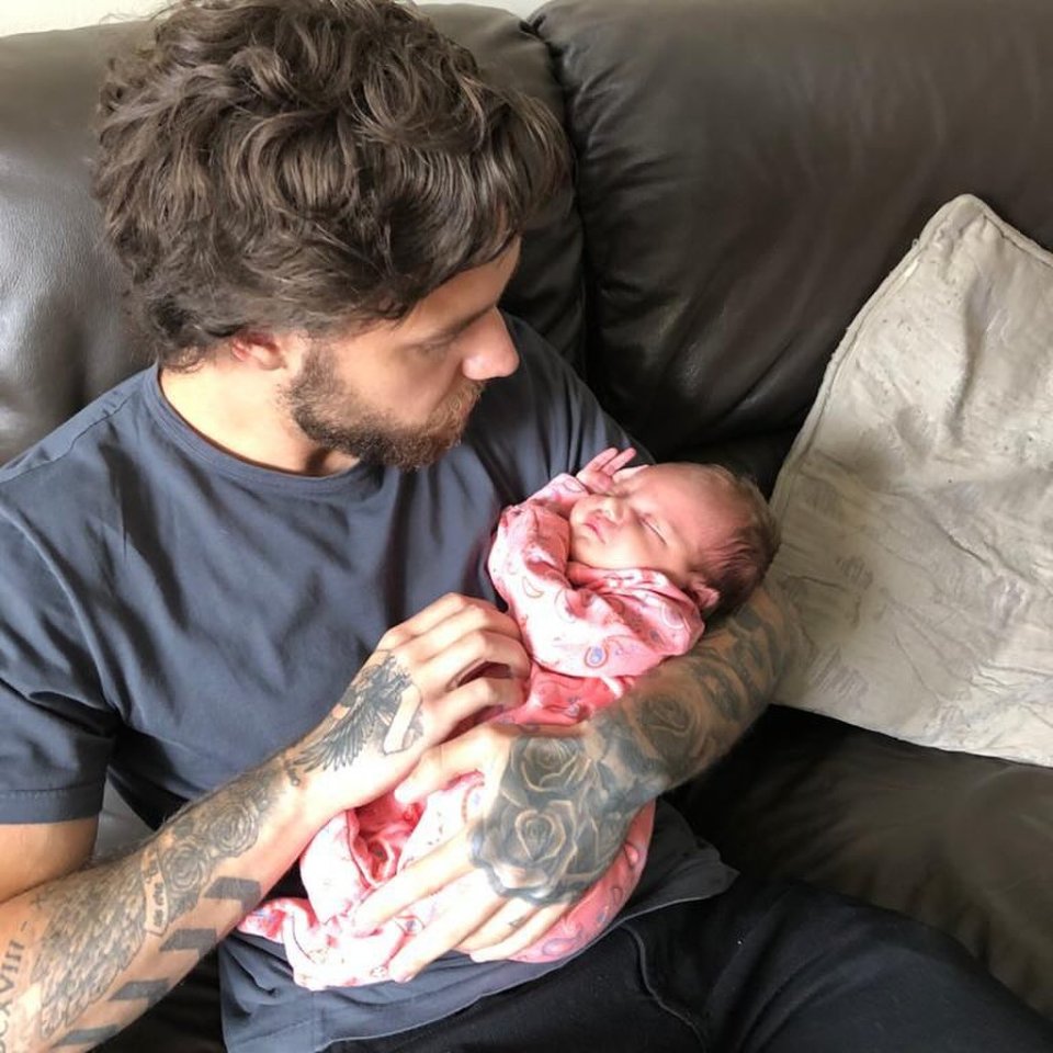 a man with a tattoo on his arm holds a baby