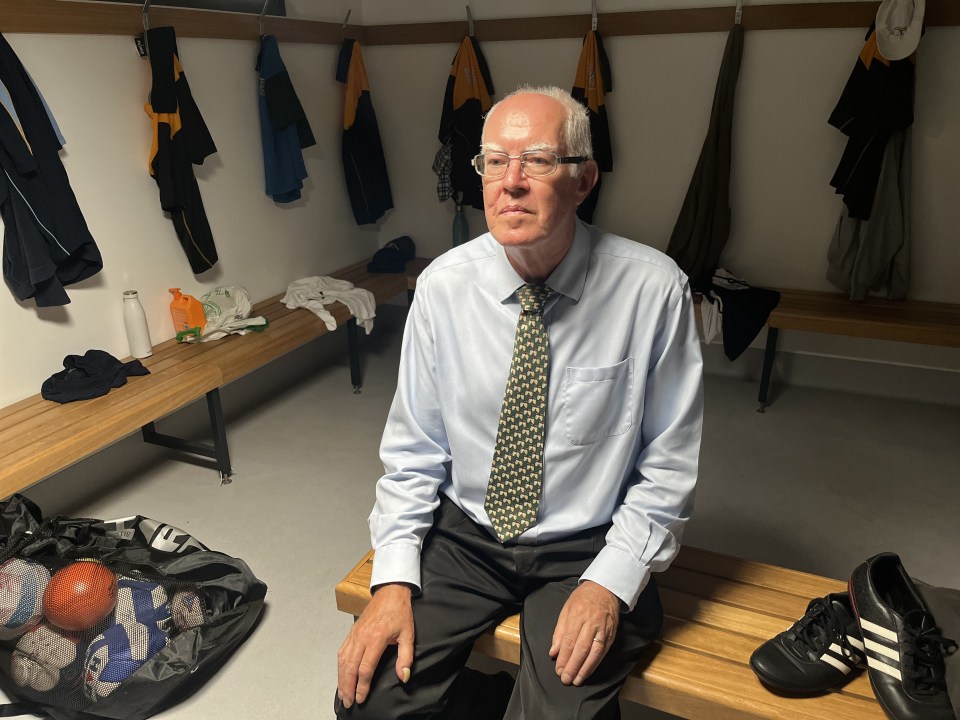 a man in a tie sits on a bench in a locker room