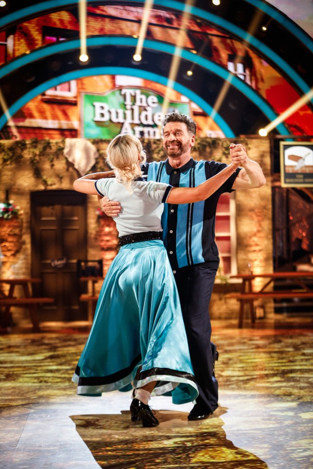 a man and woman are dancing in front of a sign that says the builde arm