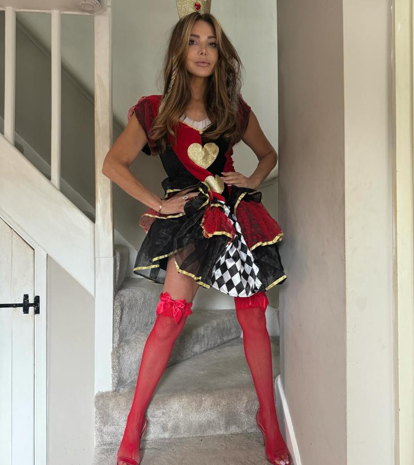 a woman in a queen of hearts costume stands on a set of stairs