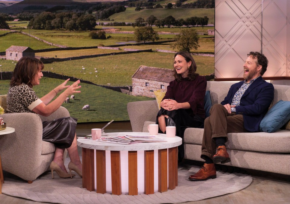 a man and two women sit on a couch laughing