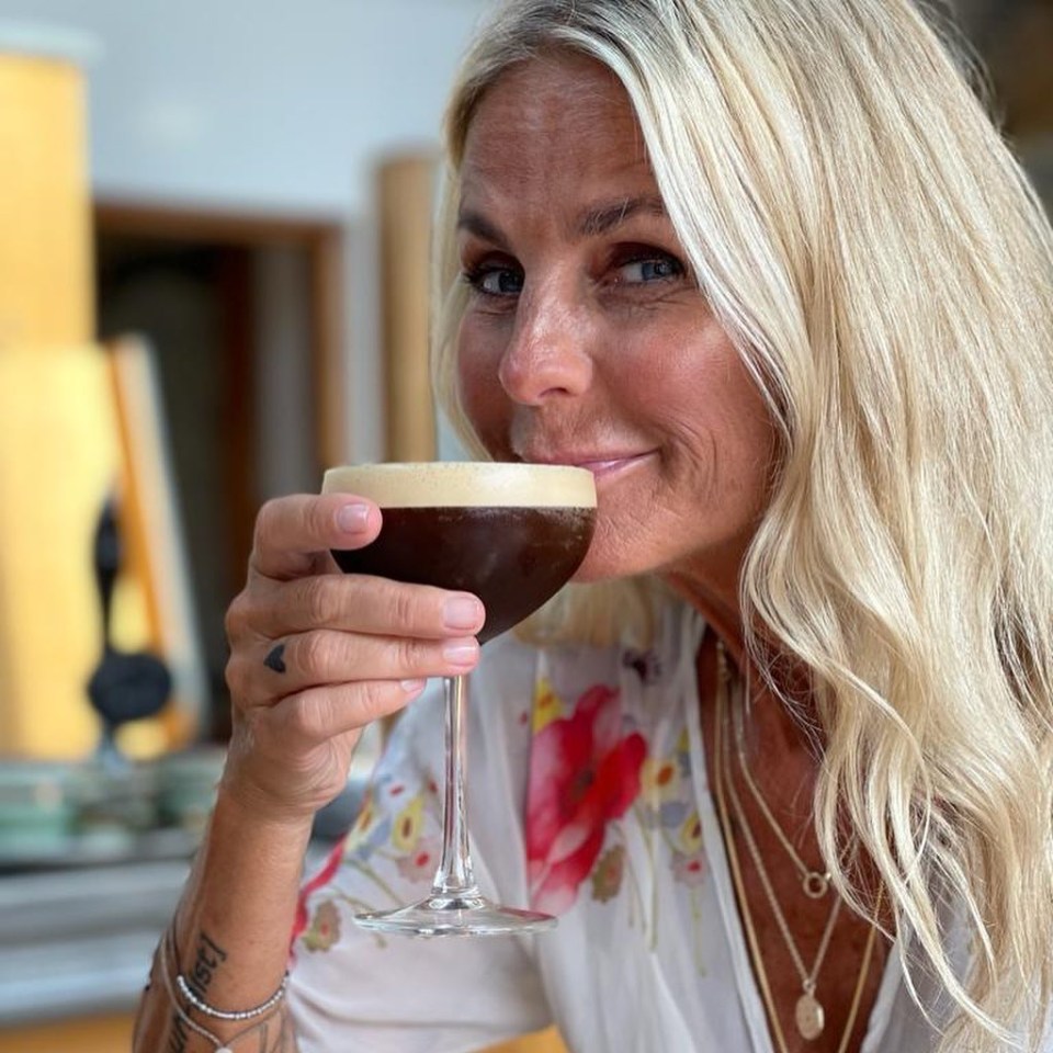 a woman with a tattoo on her arm holds a glass of coffee