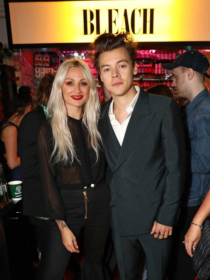 a man and a woman pose for a picture in front of a sign that says bleach