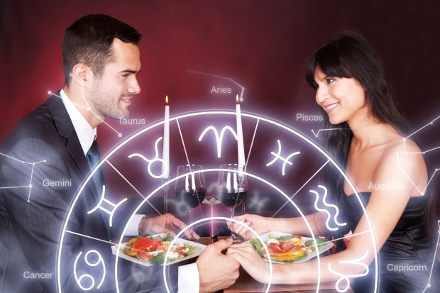 a man and a woman are sitting at a table with plates of food in front of a zodiac sign that says taurus