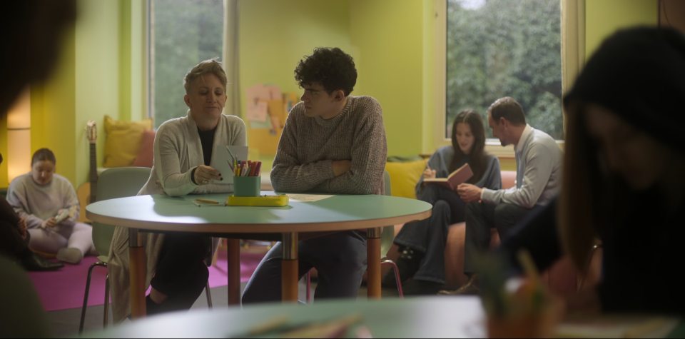 a group of people sit around a table with a yellow pencil holder on it